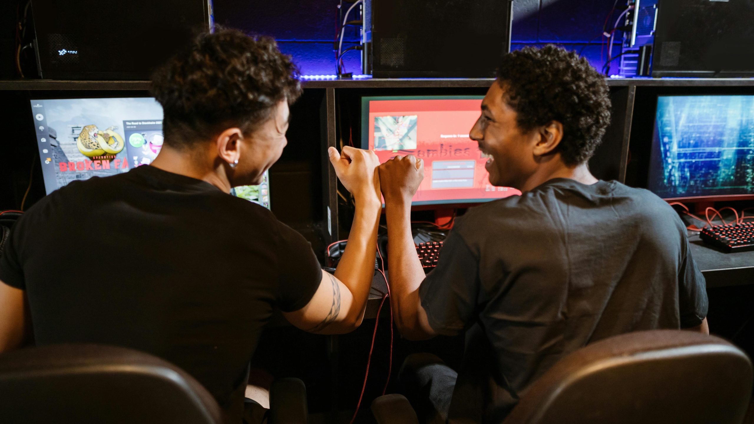 Two male friends enjoying a victory in a gaming competition indoors, showcasing teamwork and friendship.